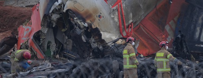 Bombeiros no local da queda do avião no Aeroporto Internacional de Muan, na Coreia do Sul — Foto: Chang W. Lee/The New York Times