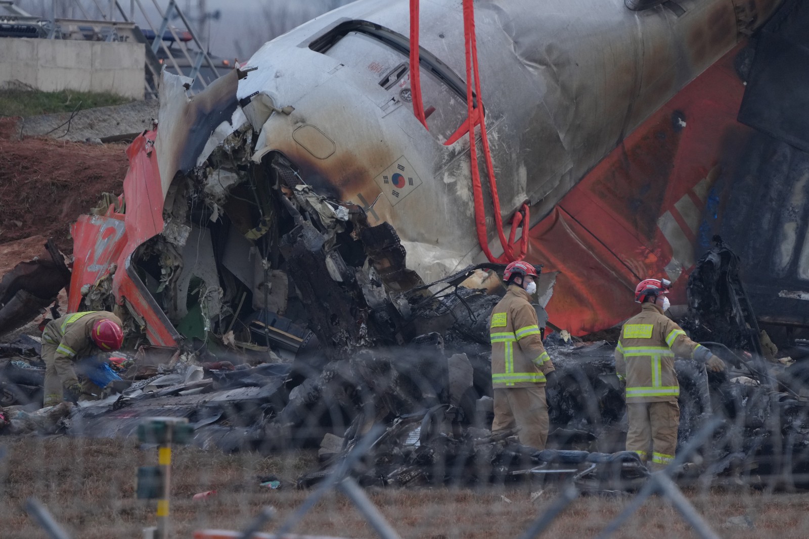 Bombeiros no local da queda do avião no Aeroporto Internacional de Muan, na Coreia do Sul — Foto: Chang W. Lee/The New York Times