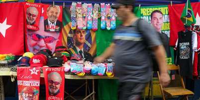 Ambulante com toalhas de Lula e Flávio Bolsonaro a venda na rua Siqueira Campos, em Copacabana, zona sul do Rio de Janeiro. Foto: Pedro Kirilos/Estadão / Estadão